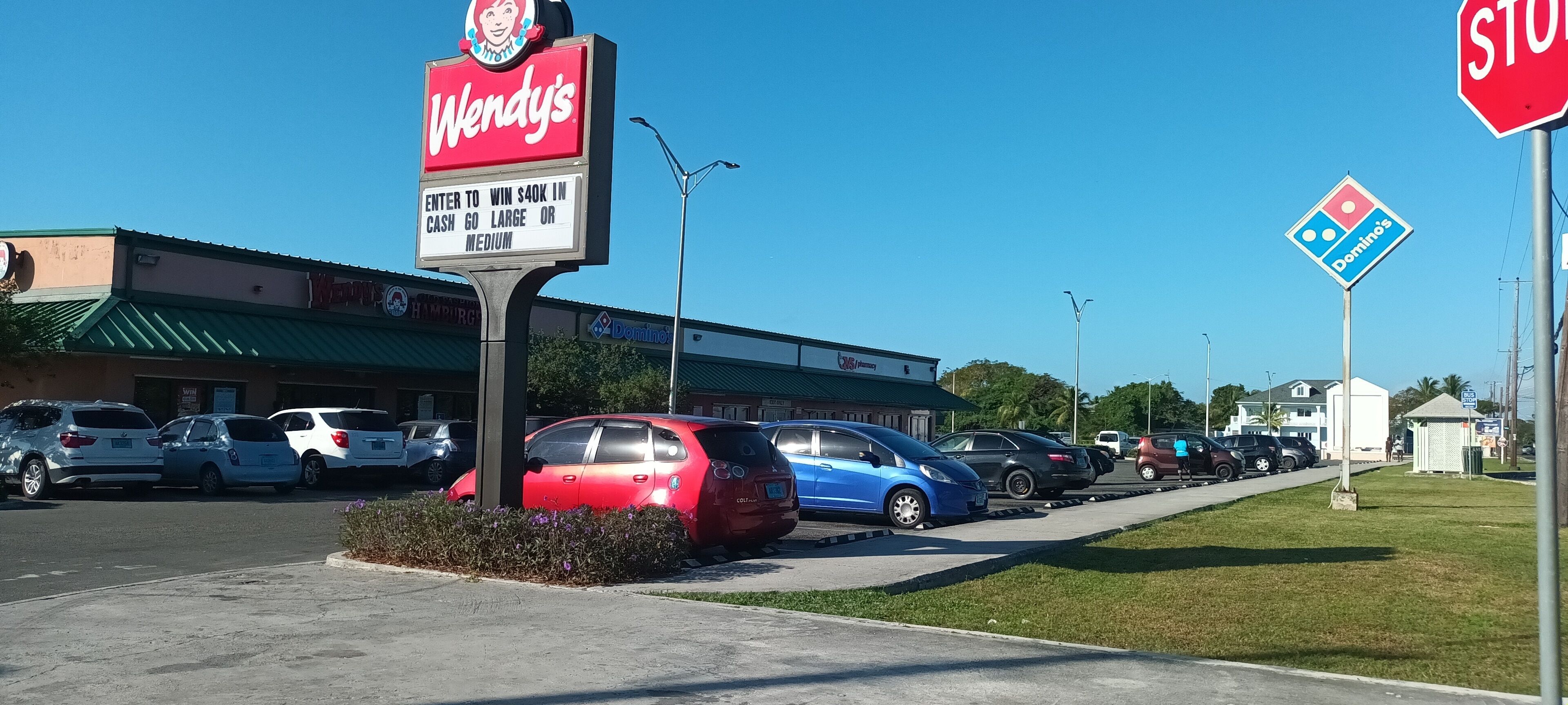 A Wendy's restaurant with a parking lot filled with cars.