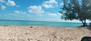 A sandy beach with a clear blue sky and a tree on the right. - Breezey Get-Away near to beach and park. Ask us about meal prep and delivery. (Nassau)