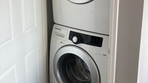 A stacked washer and dryer unit with a control panel and a detergent box on top.