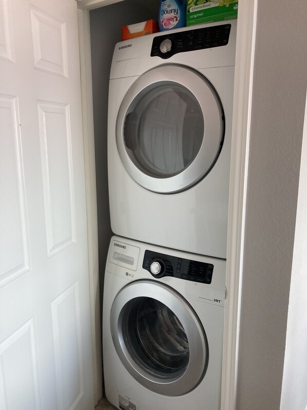 A stacked washer and dryer unit with a control panel and a detergent box on top.