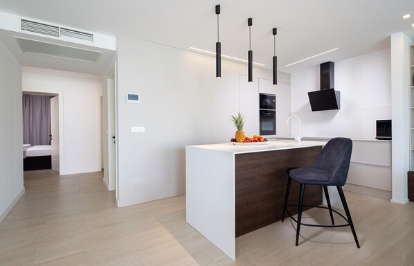A modern kitchen with a central island, black pendant lights, and a built-in oven. - Pet friendly apartment in Malinska with WiFi (Malinska)