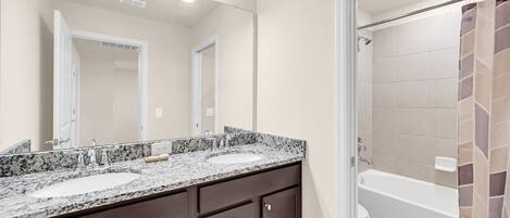 A bathroom with two sinks, a large mirror, and a shower area.