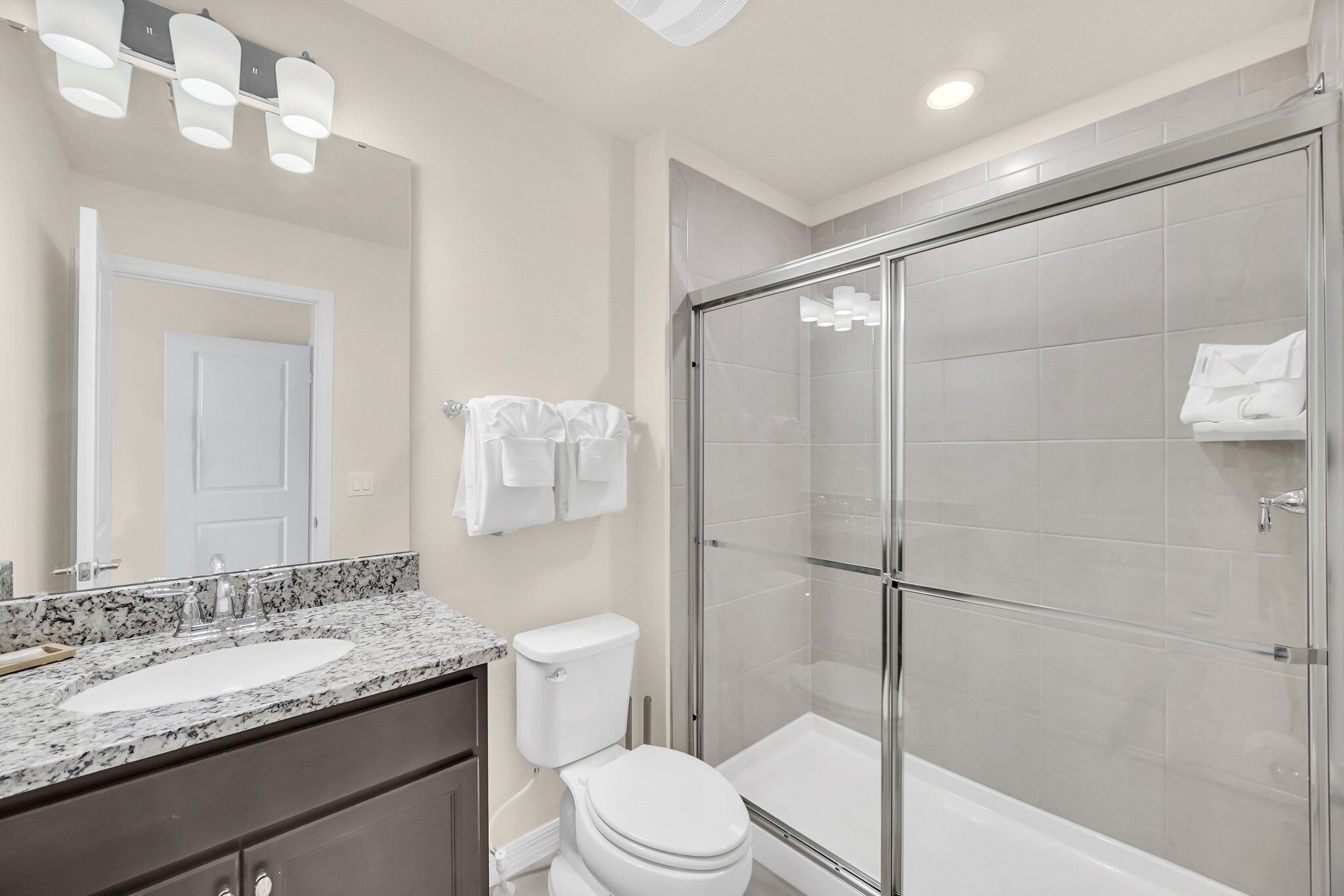 A bathroom with a glass-enclosed shower, a white toilet, and a marble sink.