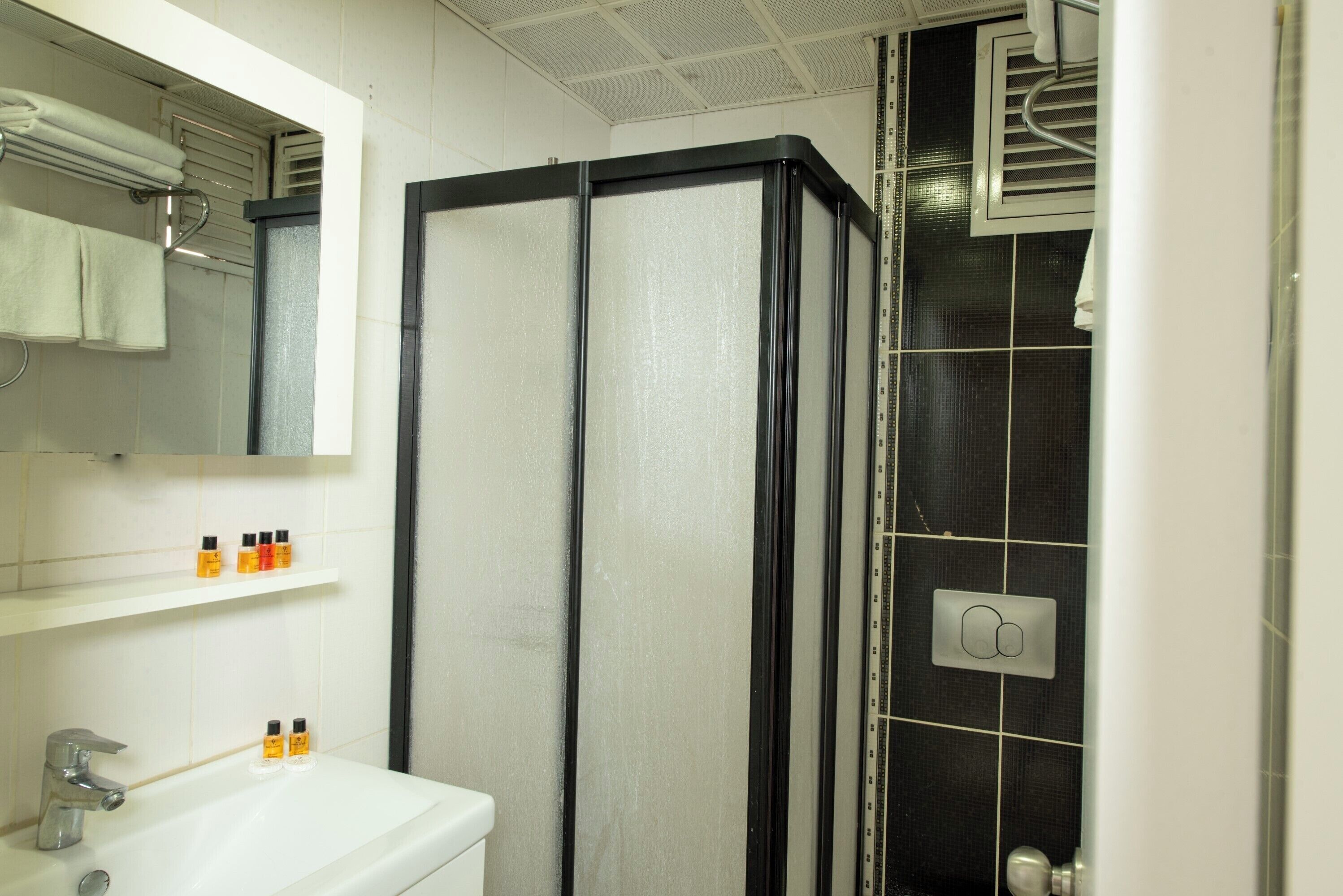 A bathroom with a white sink, a mirror, and a black shower enclosure.