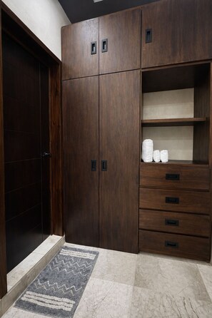 A wooden wardrobe with multiple compartments and drawers, a tiled floor, and a patterned rug. - Kasa Nikte (Tulum)