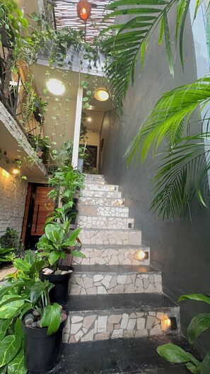 A staircase with stone steps, surrounded by lush green plants and hanging vines, leading to an upper level. - Kasa Nikte (Tulum)