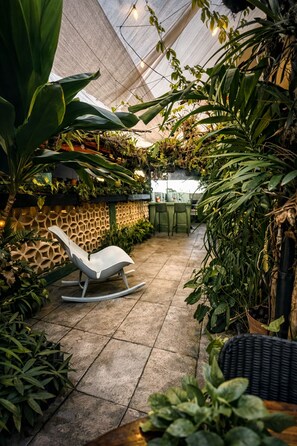 Et solarium med en liggestol, potteplanter og en mønstret væg.