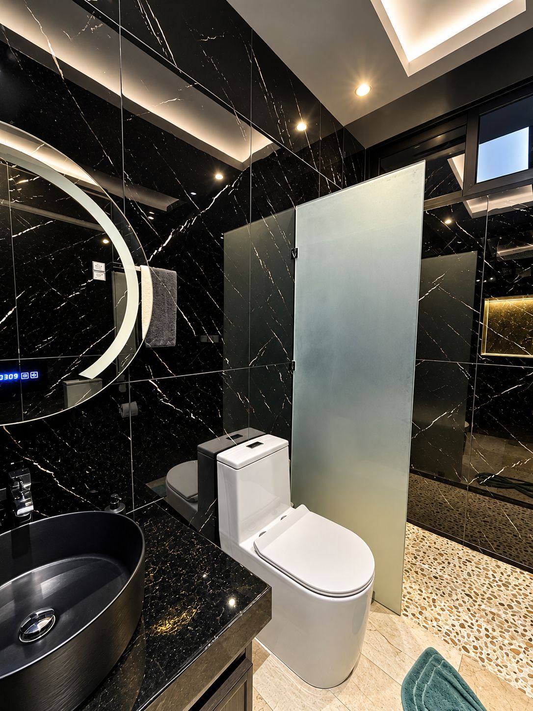 A modern bathroom with a black marble sink, a toilet, and a glass shower enclosure.