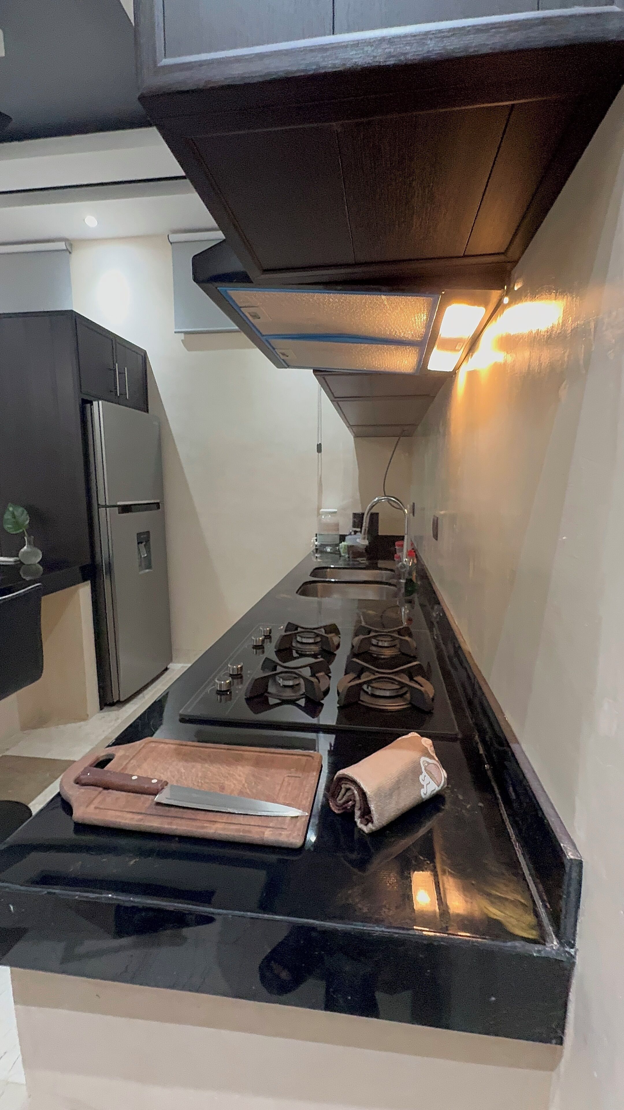A modern kitchen with a black countertop, stainless steel appliances, and a built-in oven.