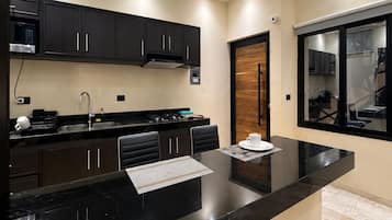Cocina moderna con armarios oscuros, encimera negra e iluminación empotrada en el techo.