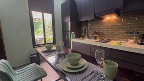 Een moderne keuken met donkere kastjes, een backsplash van baksteen en een raam met uitzicht op groen.