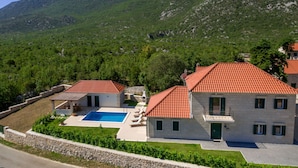 Une villa avec piscine, entourée d’une végétation luxuriante et de montagnes.