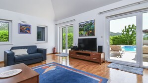 Un salon spacieux avec une grande télévision, un canapé et une table basse.