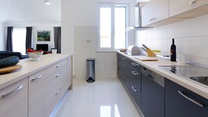 Une cuisine moderne avec des meubles de couleur claire, un évier en acier inoxydable et une fenêtre qui laisse entrer la lumière naturelle.