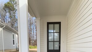 A house with a front porch, a black front door, and a brick baseboard. - Cozy Southern Retreat, 4 Spacious Bedrooms, Massage Chair, 8 Mins to Ole Miss (Oxford)