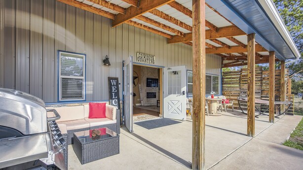A covered outdoor area with a barbecue grill, a sofa with a red cushion, and a sign reading "COWBOYS QUARTERS." - Cowboy Quarters (Larkspur)