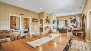 A spacious dining area with a wooden table and chairs, a foosball table, and a large wall decor piece. - Cowboy Quarters (Larkspur)