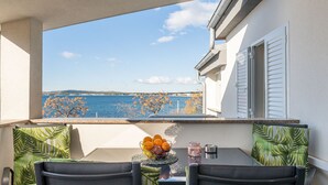 A balcony with a table and chairs, a view of the sea, and a bowl of fruit. - Tramonto by Interhome (Vir)