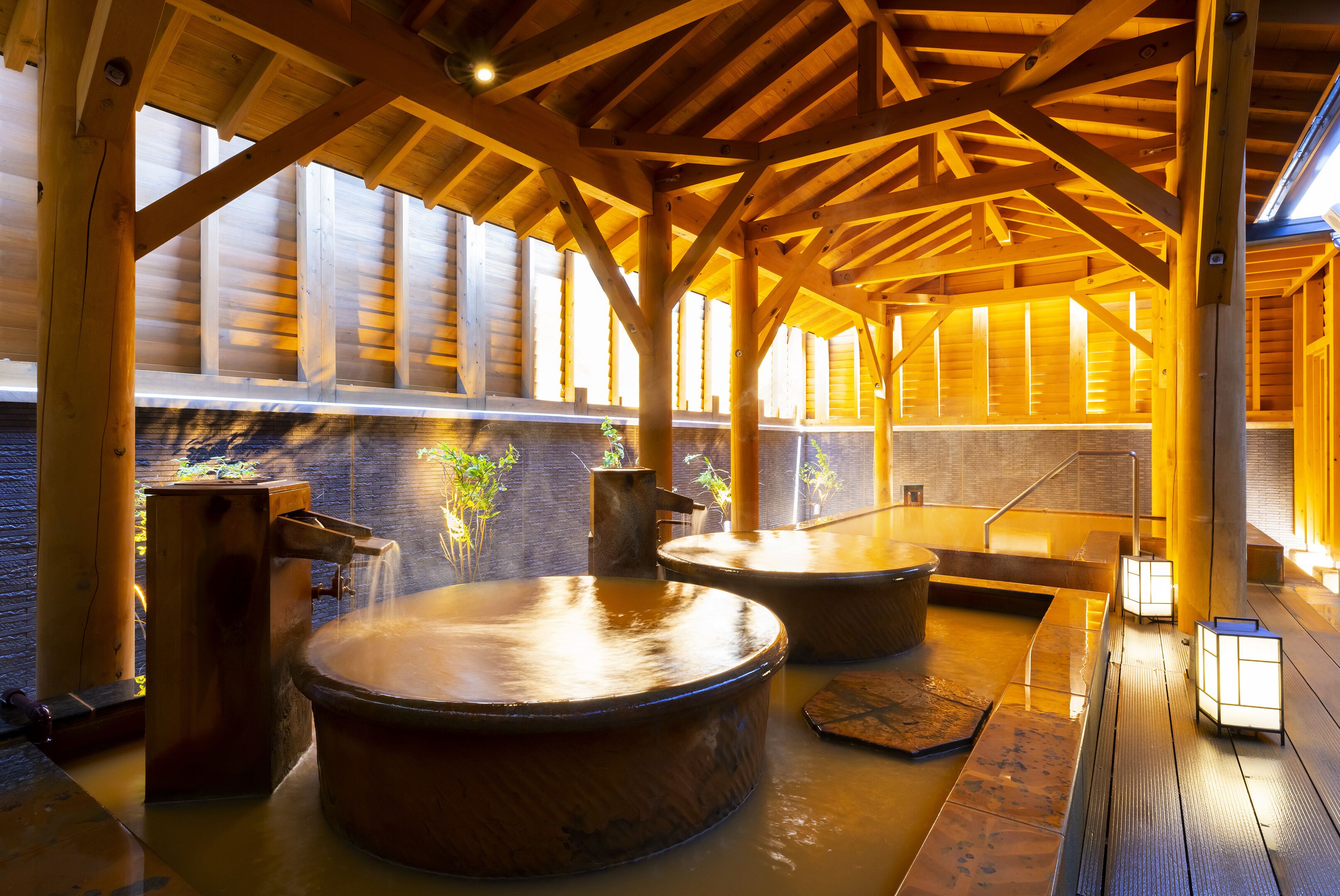 A wooden spa area with hot tubs and a stone wall.