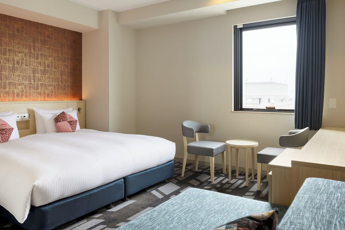 Une chambre d’hôtel avec un grand lit, un bureau, une chaise et une petite table.