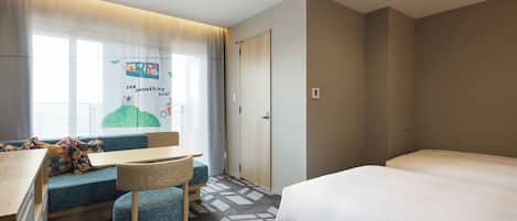 Una habitación de hotel con cama, escritorio con silla, sofá y ventana con cortinas.