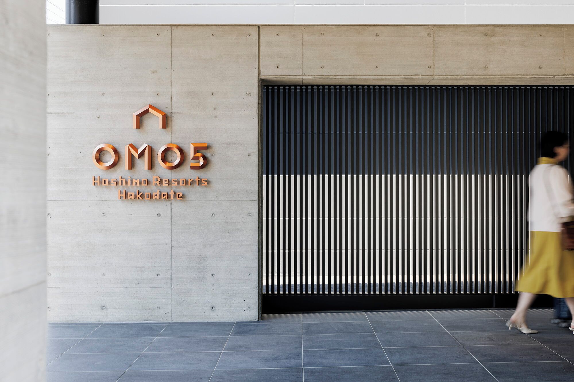 Entrada de un hotel con un cartel que dice "OM05 Hoshoino Resorts Hakodate".