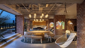 Un intérieur moderne avec une table de salle à manger ronde, des luminaires suspendus et un fauteuil suspendu.