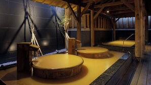 Un onsen japonais traditionnel, caractérisé par son architecture en bois et son sol en pierre.