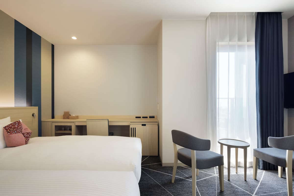 Une chambre d’hôtel avec un grand lit, un bureau, deux chaises et une petite table.