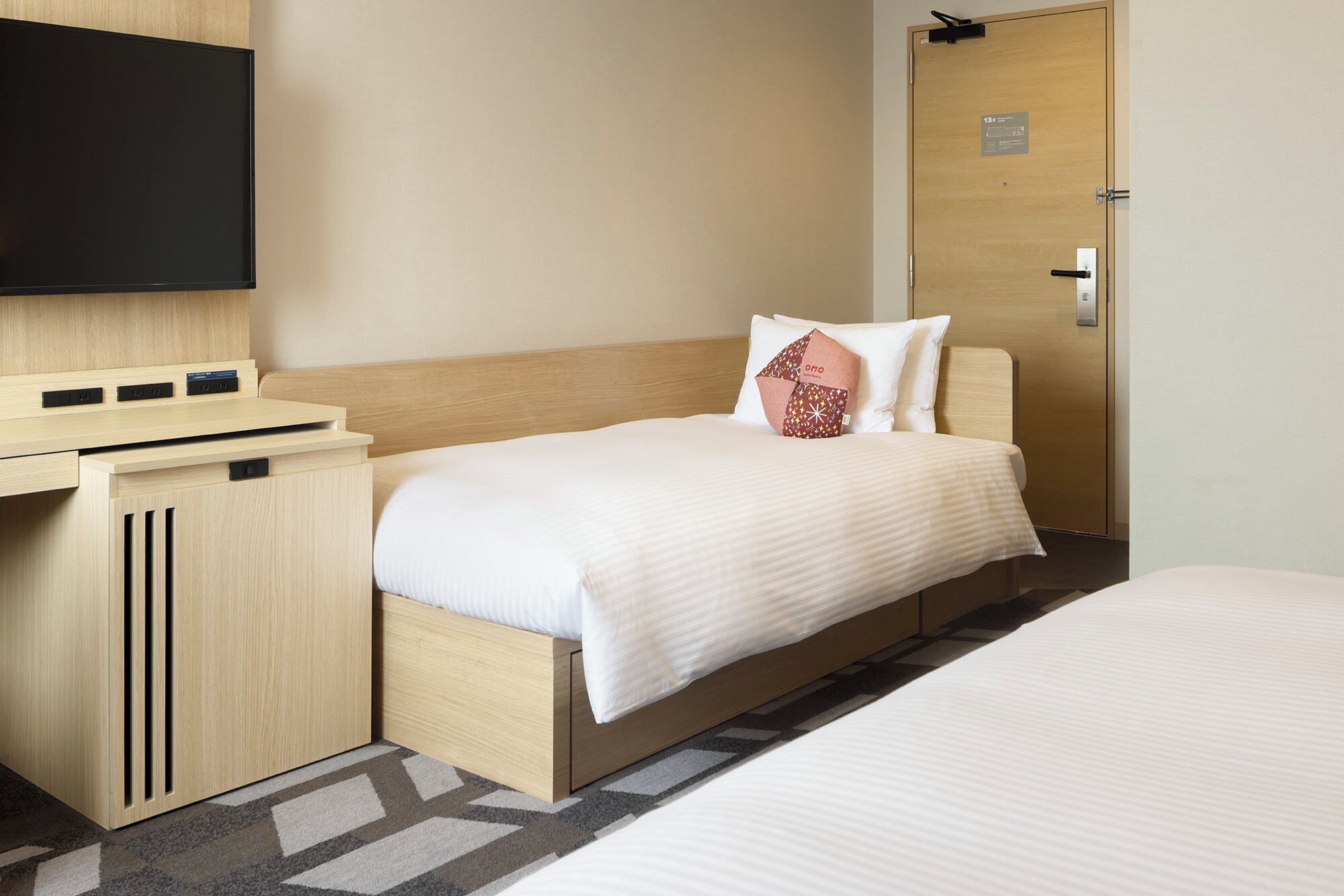 Una habitación de hotel con una cama, un escritorio con televisor de pantalla plana y una puerta con un letrero.