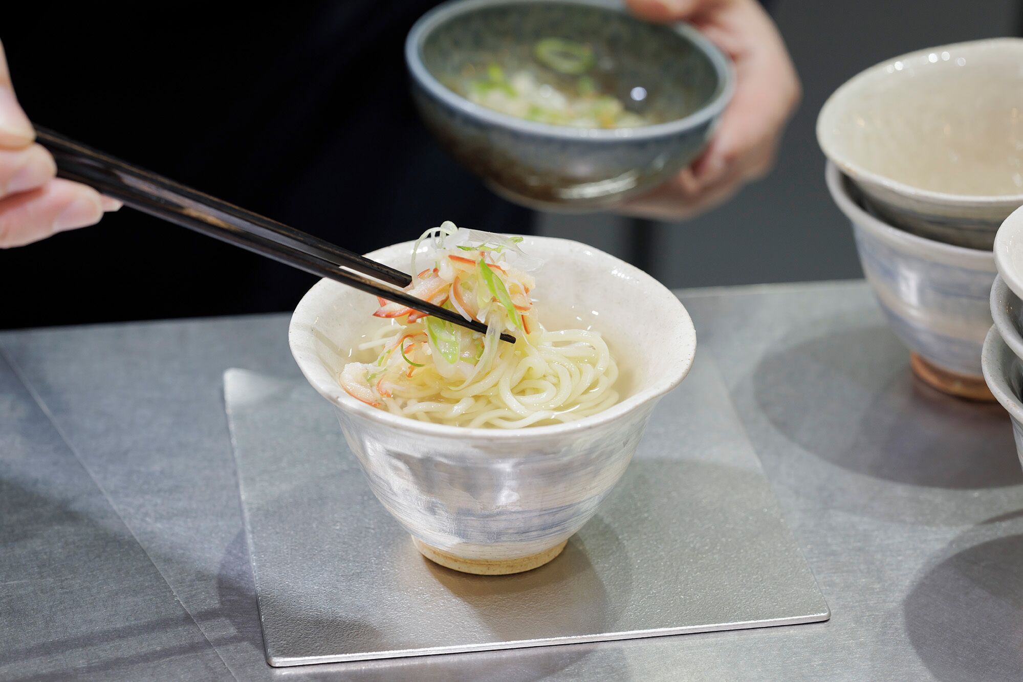 A bowl of noodles with chopsticks, held by a person.