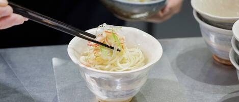 A bowl of noodles with chopsticks, held by a person.