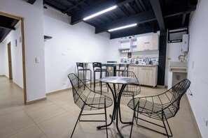 Una cocina moderna con armarios blancos, un comedor con sillas de metal y una pequeña mesa redonda.