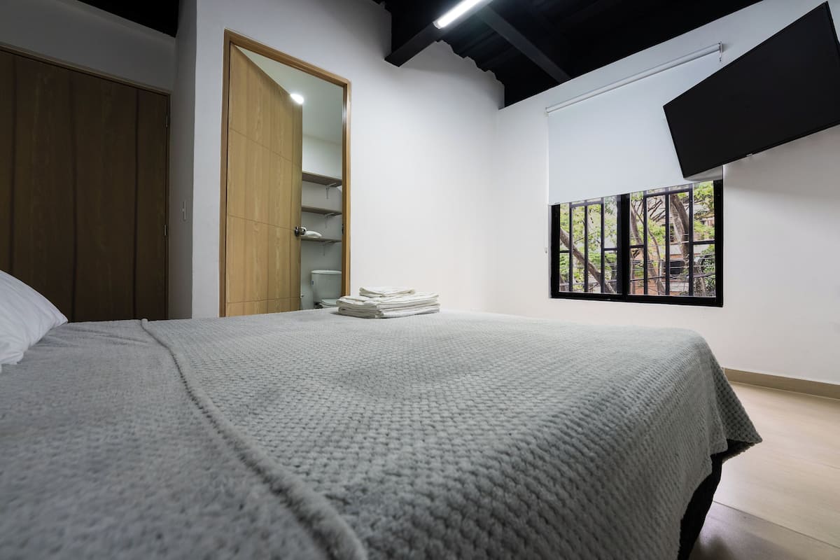 A bedroom with a bed, a wardrobe, a closet, and a window with a view.