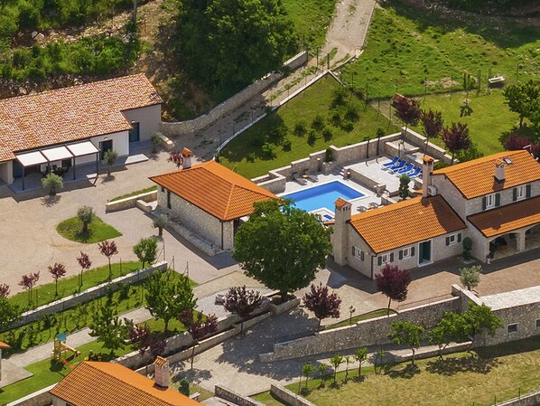 Vue aérienne d’une propriété dotée d’une piscine, de bâtiments en pierre et d’un jardin bien entretenu.