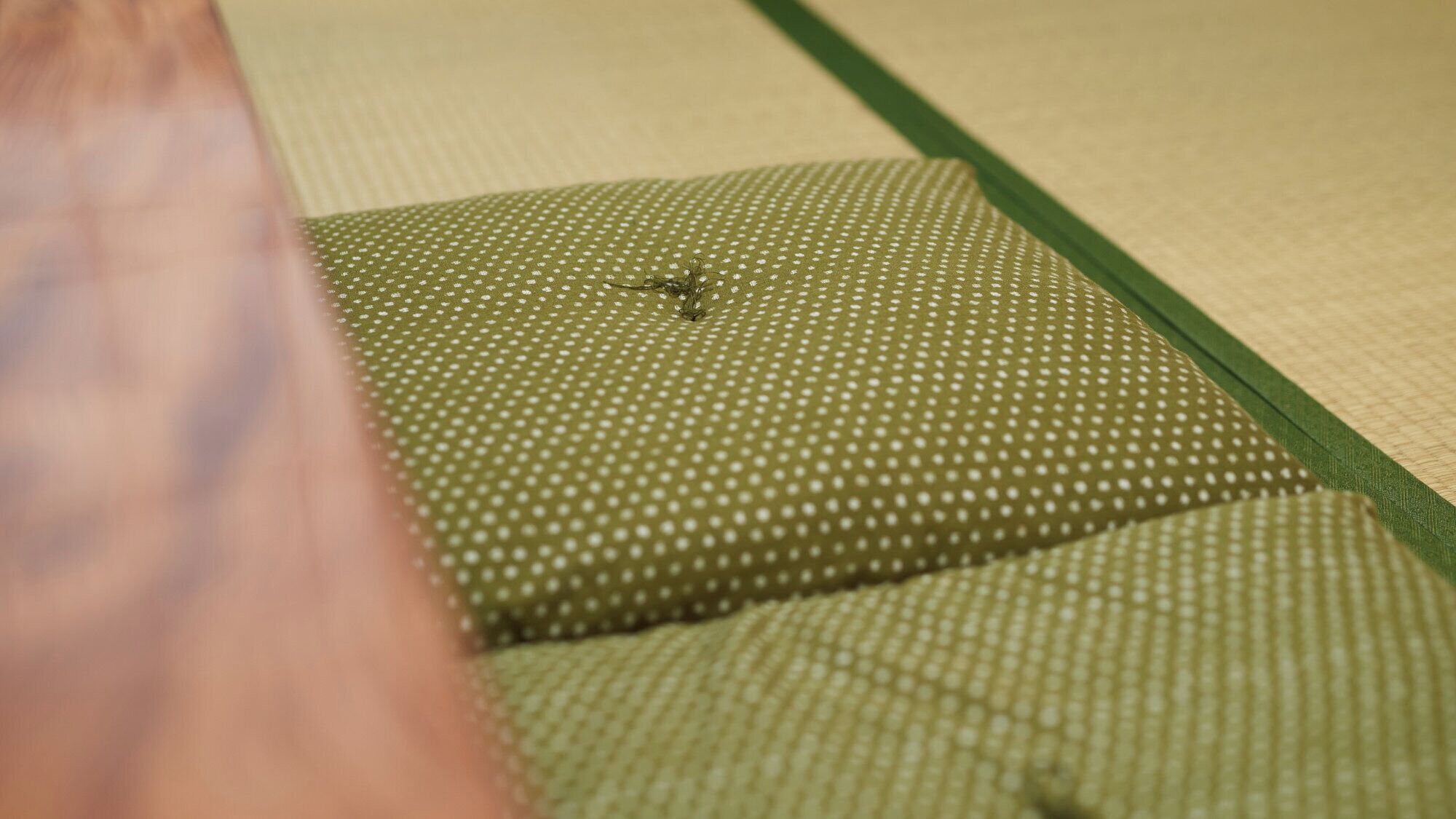 A close-up of a green patterned fabric with a small hole.