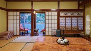 A traditional Japanese room with tatami flooring, a low table with a tea set, and sliding doors with a view of greenery outside. - Hayamasou (Tokamachi)