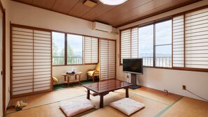 A traditional Japanese room with tatami flooring, a tatami mat table, a television, and a view of the outdoors through shoji screens. - Hayamasou (Tokamachi)