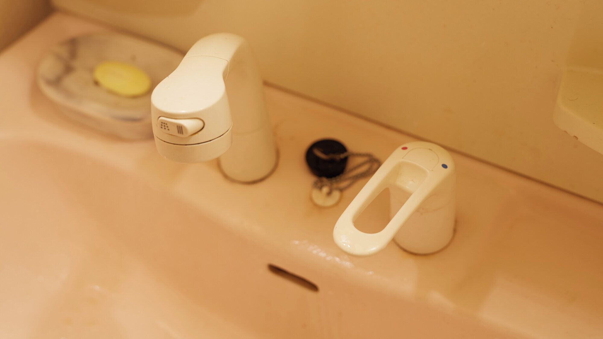 A bathroom sink with a soap dish, a faucet, a soap dispenser, and a bidet.