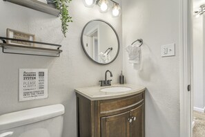 Een badkamer met een wastafel, spiegel en een bord met informatie over de sanitaire voorzieningen.