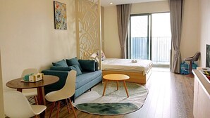 A modern hotel room with a bed, a sofa, a dining table, and a TV. - Vinhomes Dcapital Managed by Anstay Residence (Hanoi)