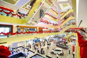 A multi-level shopping mall with escalators connecting floors, various stores, and a red carpeted area.