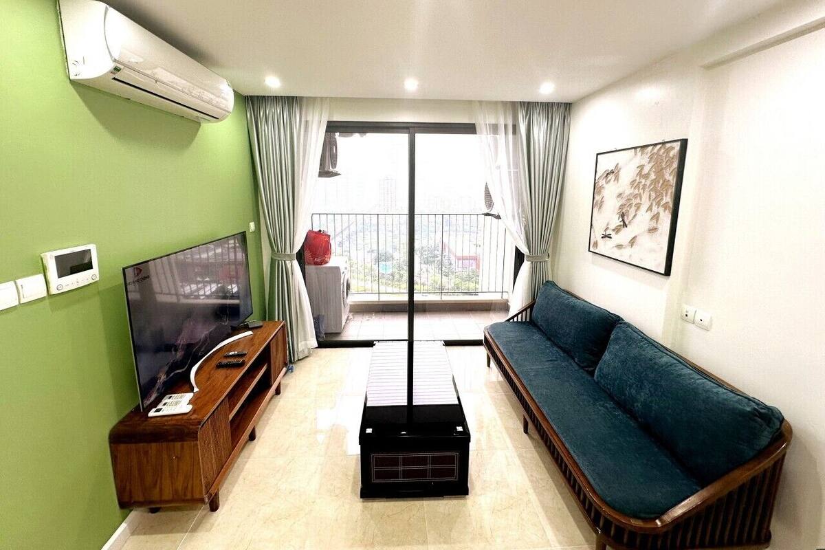 A living room with a TV, sofa, and a balcony with curtains.