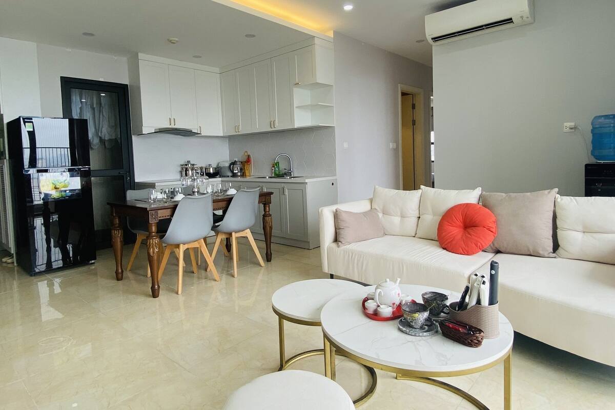 A modern living room with a white sofa, a coffee table, and a dining area with a table and chairs.