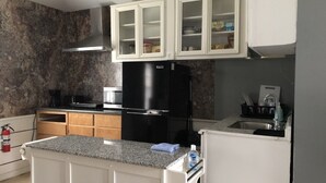 Une cuisine dotée de plans de travail en granit, de meubles blancs, d’un réfrigérateur noir et d’un four encastré.