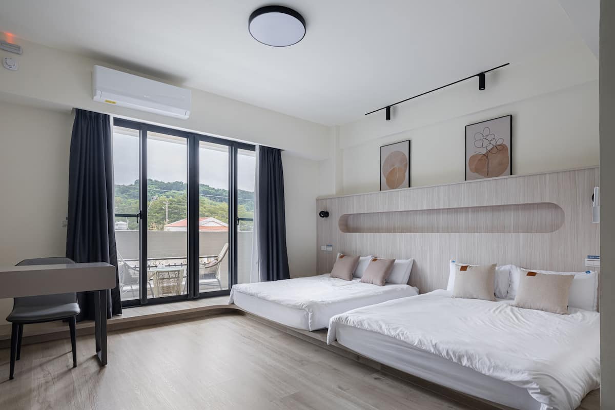 A hotel room with a bed, a desk, and a view of the outdoors.