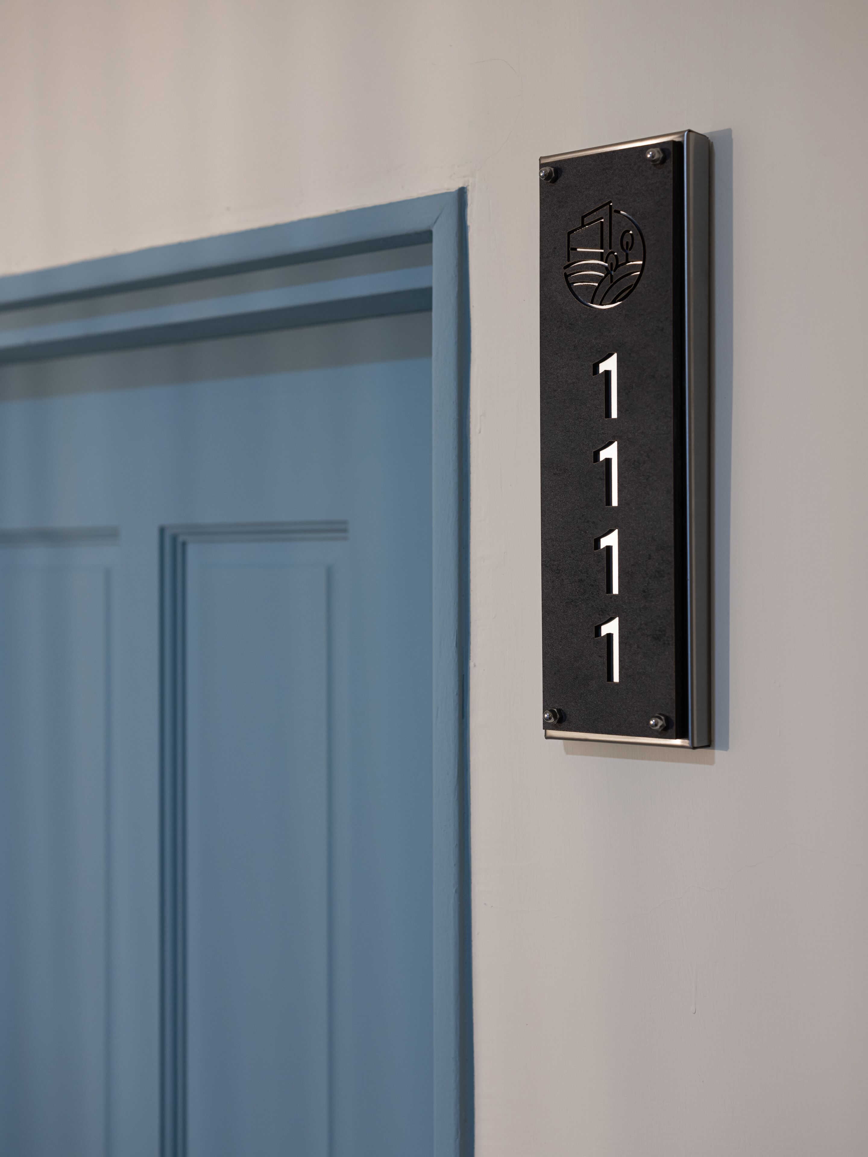 A blue door with a black sign displaying the number 1111.