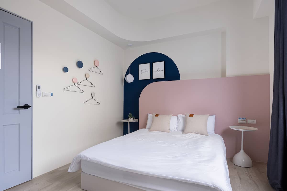 A modern bedroom with a bed, bedside tables, and a wall-mounted coat rack.