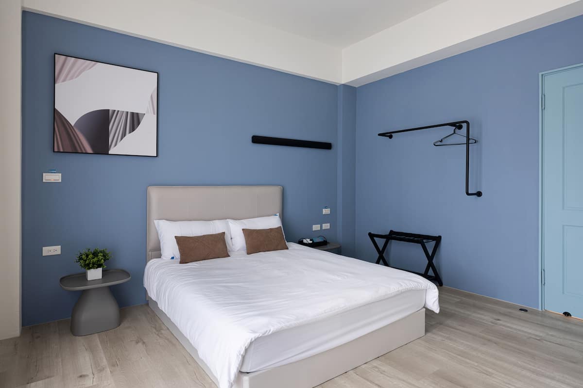 A modern bedroom with a bed, bedside table, and a small plant.