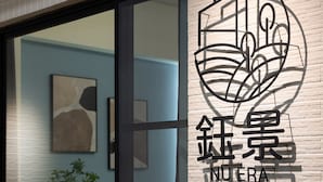 Un interior moderno con un amplio ventanal, un logotipo montado en la pared y una planta.